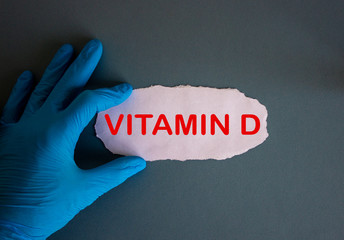 Hand in blue glove with white small paper. Concept word vitamin d.
