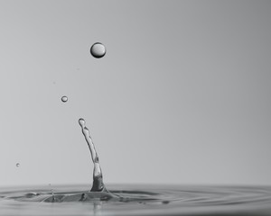 Múltiples gotas de agua cristalina chapoteando en una superfície de agua calmada y formando ondas...