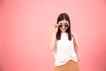 Portrait of a young woman with glasses on a pink background.