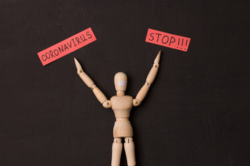 Figure of wooden man asks coronavirus to stop. Pandemic, panic, recovery, red words on a black...