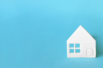 Little house of white paper on light blue background.