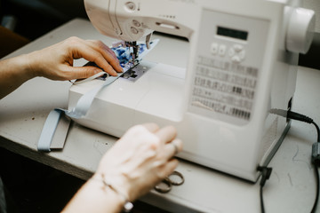 Woman sews homemade face mask because of the protective mask requirement during corona virus pandemic.
