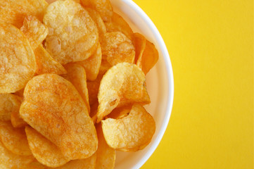 Plate with potato chips on a bright yellow background.