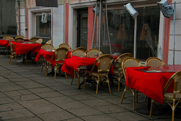 strong wind picking up red tablecloths on tables in an outdoor cafe