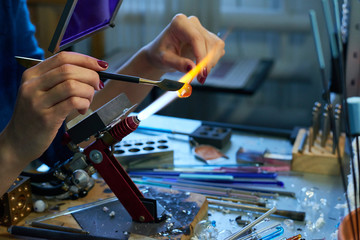 Hands of young craftswoman with hand tool cutting edge of glass workpiece