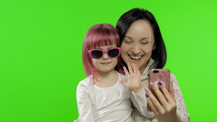 Mother, daughter holding, using smart phone talking on video call. Social media