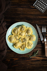 Traditional italian ravioli with rosemary and parmesan served on a rustic wooden table. Italian pasta. Top view, copy space