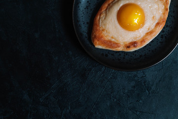 Khachapuri boat with egg in Adjara on a black background.