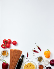 Groceries on white background: red and yellow bell peppers, dried chili, oregano, curry, allspice, red onions, farfalle pasta, bottle of olive oil, spaghetti, tomatoes at the bottom of the frame