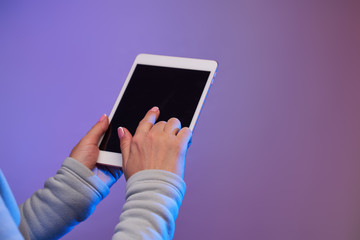 Close-up of man's hands with smartphone and blank black screen on blank purple background.