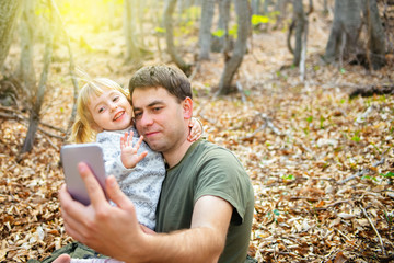 Dad and child make a video call online to family or friends and wave their hands at the camera.