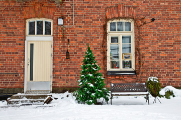 an old door and window . brick wall of red color with christmas tree infront