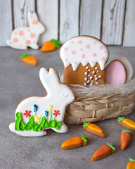 Easter gingerbread on a gray and wooden background with a wicker basket. Gingerbread in the form of a hare, carrot, egg and cake. Copy space. The concept of the Easter holiday and handmade. Vertical