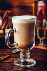 Irish coffee with cinnamon on wooden surface