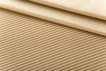 Carton or cardboard packing material. Texture of corrugated paper sheets made from cellulose. Supplies for creating boxes and packaging. Pasteboard background. Natural brown cardboard surface.