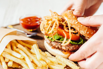 Fast food. Traditional American cuisine. Burger in female hands. French fries bbq sauce.