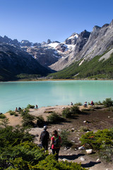 Gente caminando en un lago entre montañas nevadas en un día soleado