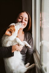 young woman and her cute dog at home by the window.