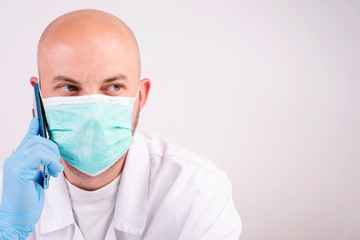 Fototapeta na wymiar Man in face mask on white background with copy space talking by phone and makes a medical visit. Health care and protection while pandemic and covid-19. Business during quarantine and coronavirus.
