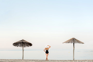 Girl in a hat stands on the beach