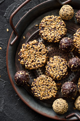 Raw vegan snack. Homemade energy bites and cookies with flax seeds in metal tray on dark background