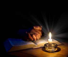 Hands folded in prayer over Scriptures