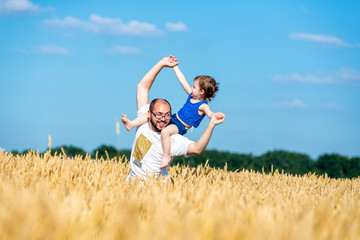 Fototapeta na wymiar father and son having fun outdoor in wheat field
