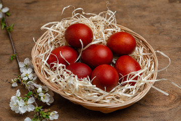Fototapeta na wymiar red easter eggs in wicker basket on wooden background