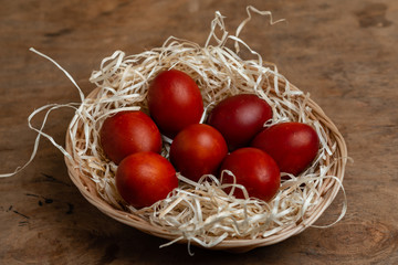 red easter eggs in wicker basket on wooden background