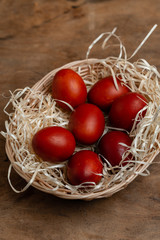 red easter eggs in wicker basket on wooden background