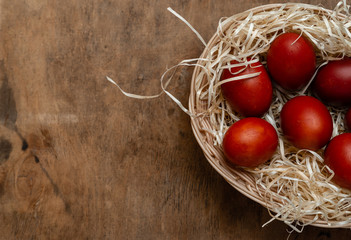 red easter eggs in wicker basket on wooden background
