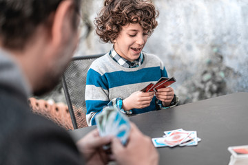 Father and son having fun playing card game sitting on the rooftop table in quarantine for the...