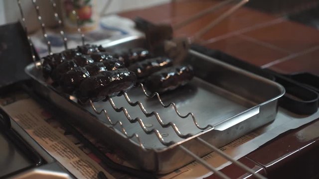 Grilled blood sausages served with tongs on a metal tray