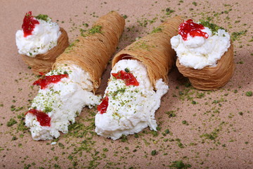 A slice piece of Esmalliyeh Ramadan Arabic sweet pastries & dessert with creamy & pistachio