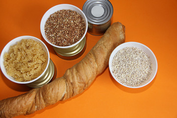 long-term storage food cereals, stew, sprats, bread and canned food on an orange background