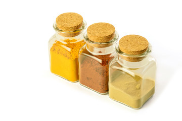 Cuisine spice turmeric powder, hot red pepper and laurel powder in glass bottles on the white background isolated.