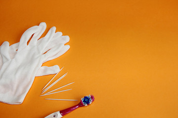 white protective gloves toothpicks and a toothbrush on an orange background