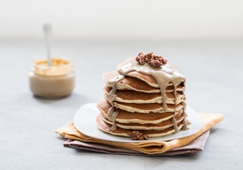 Pancake with nut paste, granola, nuts on a plate on a light background