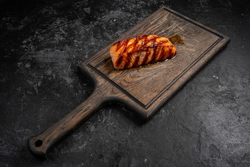 Grilled salmon with soy sauce and herb by lemon served on a wooden board