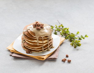 Pancake with nut paste and granola on a plate on a light background