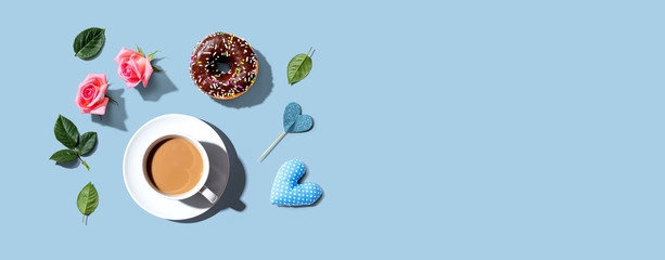 A cup of coffee with pink roses and a chocolate donut