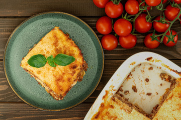 Classic Italian lasagna piece at plate on wooden table from above, healthy food