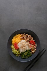 Traditional Korean dish Kuksi on a dark background (one of the types of Kuksi). Ingredients- pasta, vegetable salads of cucumbers, cabbage, radish, meat, omelet. The broth is served separately.