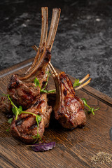 Grilled lamb ribs on cutting board. Hot rack of lamb with spices and condiments. Top view on wooden...
