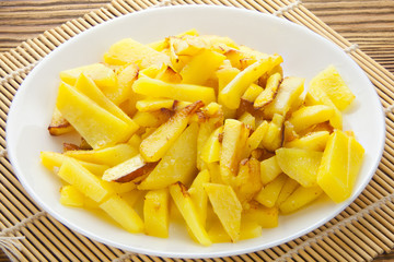 delicious fried potatoes on plate on white background