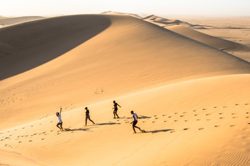Fototapeta na wymiar Children running, playing and climbing up on dune 7 in namibia desert