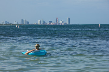 persona descansando en el mar y de fondo la gran ciudad