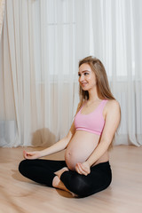 Fototapeta na wymiar A pregnant girl does yoga at home. Health