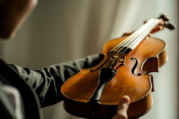 close-up photo of classical instrument violin in male hands. man holding violin before performing music with the use of it © alfa27