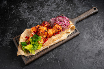 Grilled chicken pieces on skewers with sauce. Octoberfest party dinner. Festive table with delicious food on black boards.
